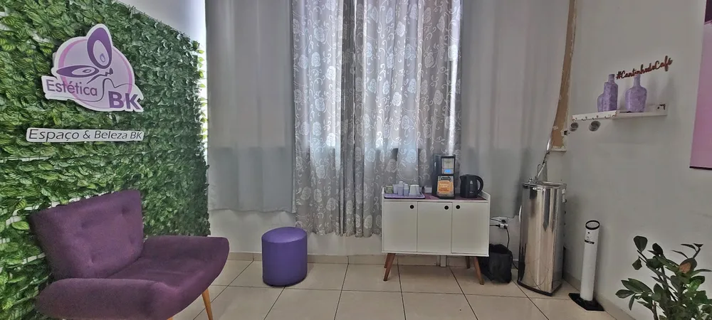 Recepção e lounge da Estética BK, com sofás lilás e o painel da marca